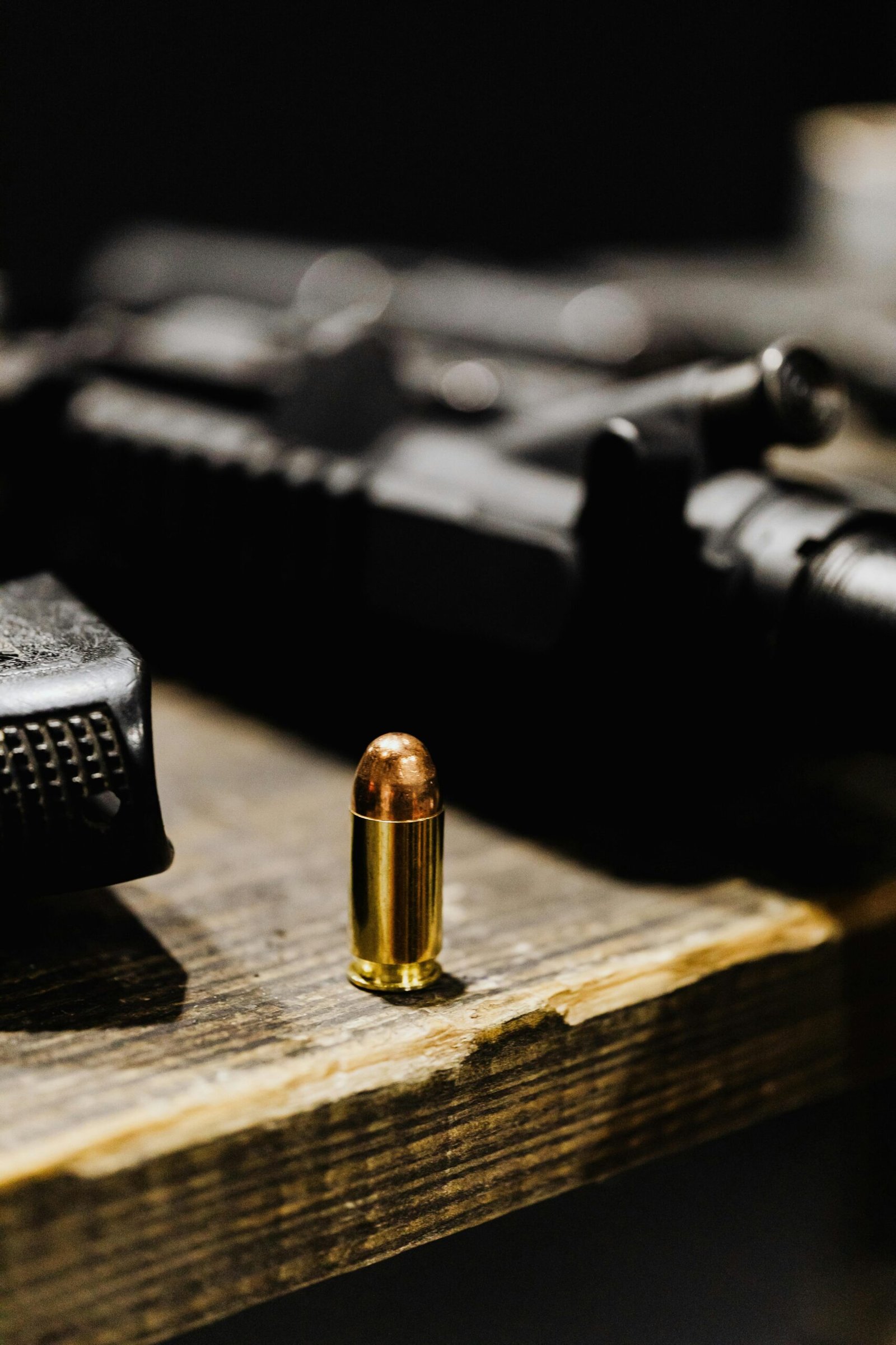 A focused view of a bullet standing upright on a rustic wooden surface.